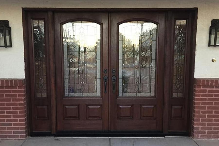 large hardwood front double doors with large arched windows, with patterned glass windows on both sides