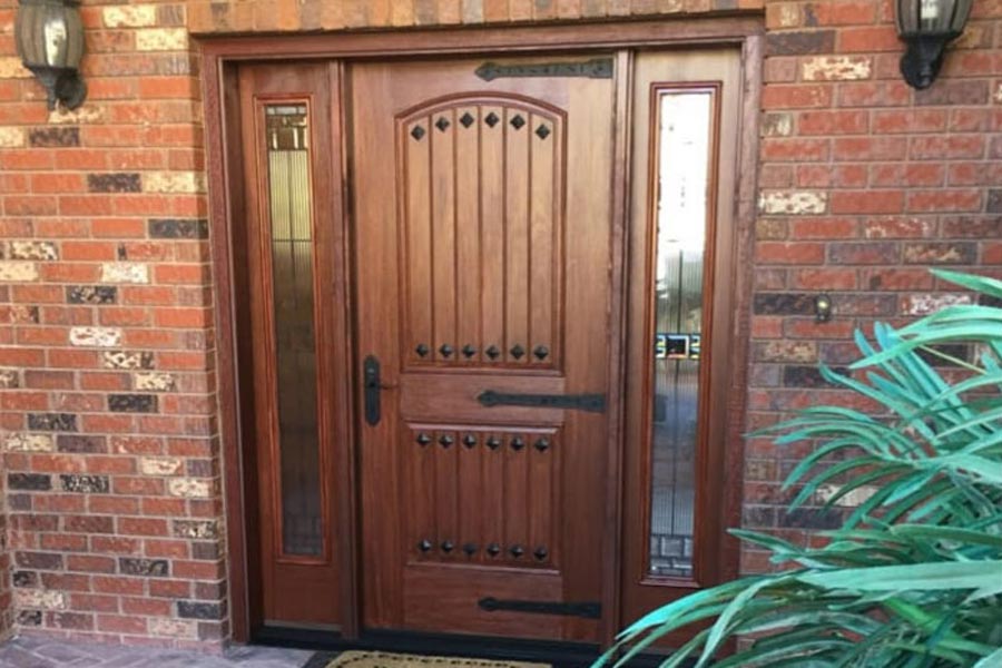 wooden door with no windows built in and arch design with sidelights complementing brick home