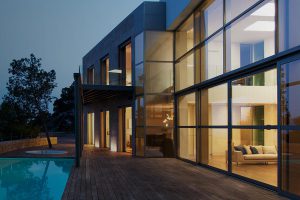 large picture windows from two stories of large house overlooking pool and letting natural light into home