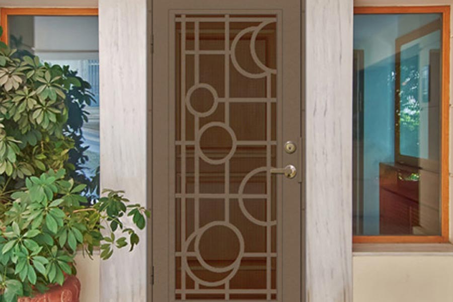 art deco door screen with moon and circle shapes and large picture windows on porch of house