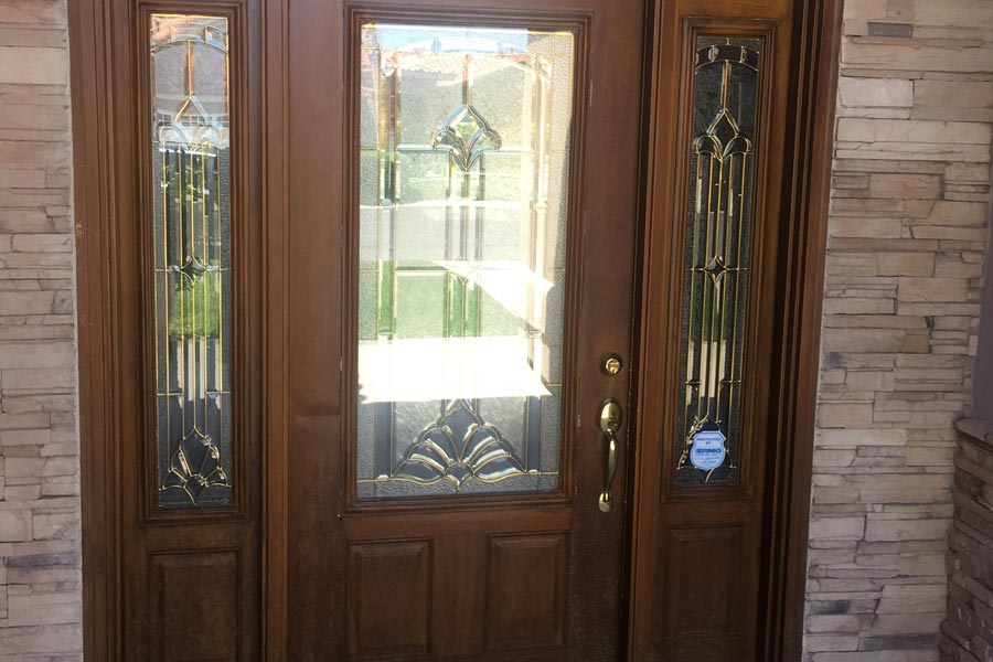 Wooden front door with patterned glass top half, and sidelights to match with patterned glass windows
